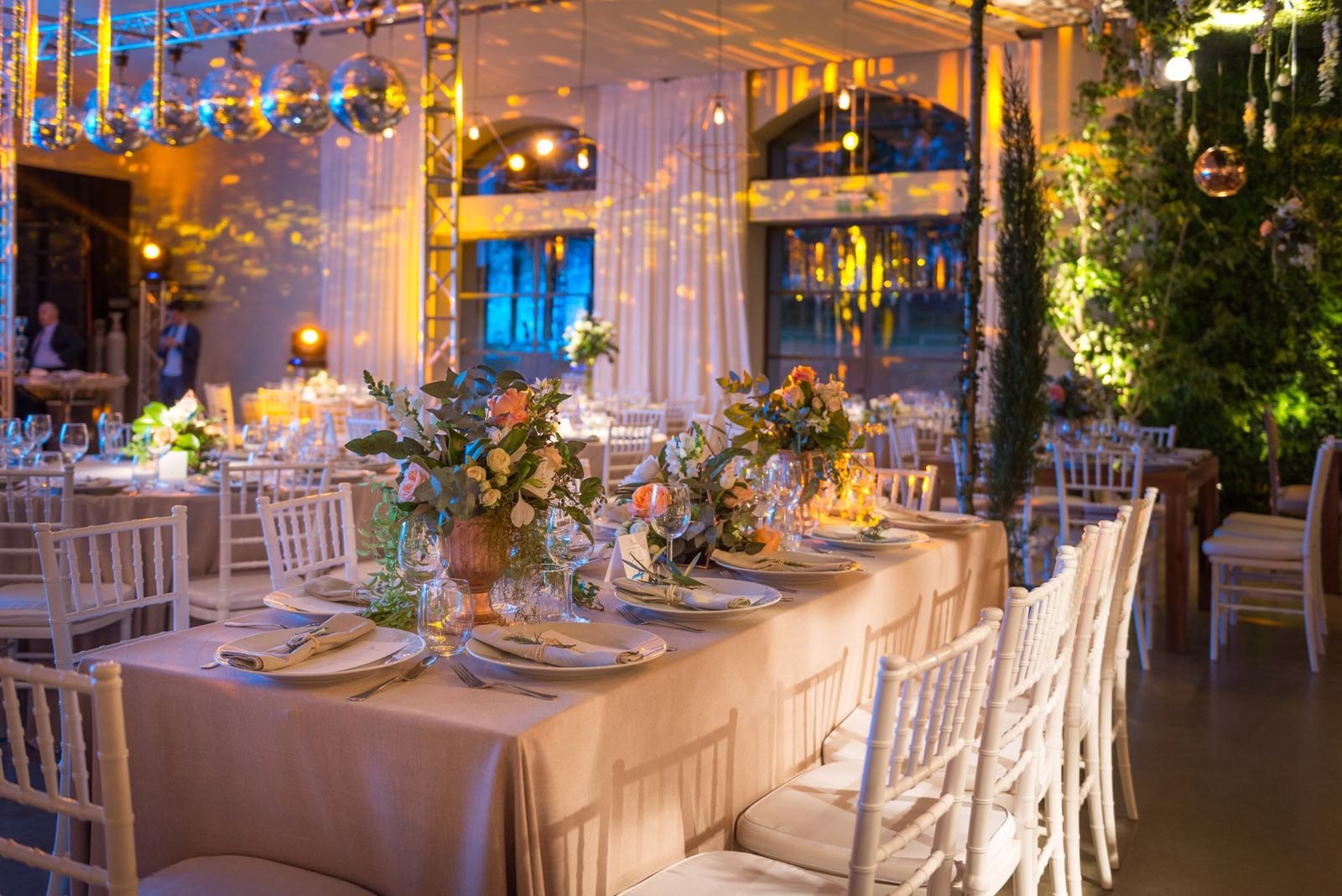 Boda con mesas largas y flores bajo un techo verde
